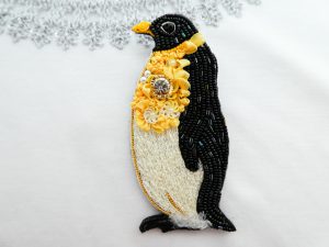 ペンギンのブローチです。胸元に大きなクリスタルとリボン刺繍があり華やかな感じです。