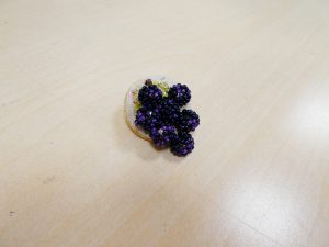 揺れる葡萄の実がついた円形のブローチです。