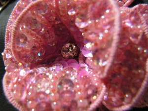 チャームの中心にクリアなストーンが1つあります。花びらの外側はオーロラピンクですが、内側は濃いピンクで刺しています。