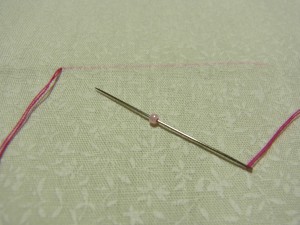 図案線の端から糸を出したらビーズを、ひと粒針に通します
