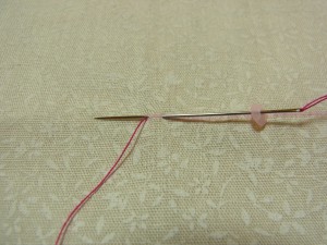 スパンコールの半径分で生地をすくい、最初の糸部分に針を戻します