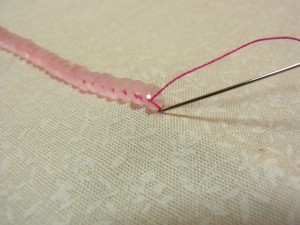 スパンコールの糸部分に重ねて針を落とし裏側で玉止めをします。