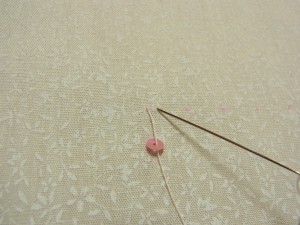 スパンコールの穴から針を通し、右側へスパンコール半径分の位置に針を落とします。