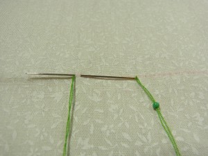 ビーズの幅で生地をすくい、最初の糸が出ている部分に針を戻します。