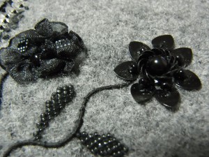 黒いハート型のスパンコールを使った花と、オーガンジーリボンをフリルのように作った花が2本あります。
