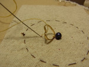 印から針を出しパーツに糸を掛けて、再び印のところに針を落とします。