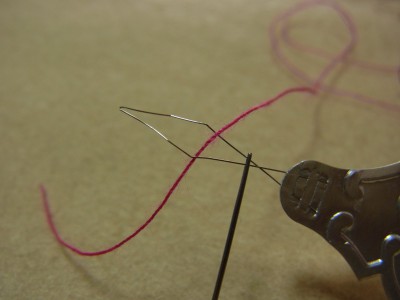 針穴に針通し道具の先端（ひし形）部分を入れます。そこへ糸を通します。
