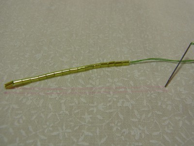 6㎝の図案線を2本書きます。16粒の竹ビーズを通した糸を、図案線の端から端に針を落とします。