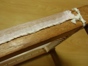 木枠の横棒に、生地をタコ糸1本どりで縫い止めます。